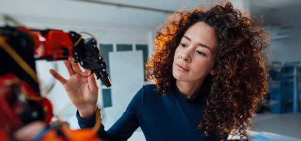 Engineer-examining-robotic-arm-in-office