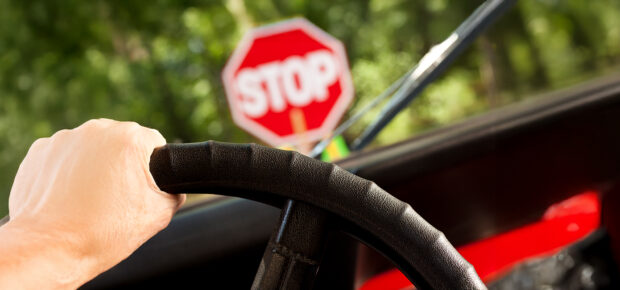 Adult driving jeep stopped at construction stop sign or school crossing sign.