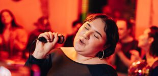 Carefree woman with eyes closed singing karaoke at bar