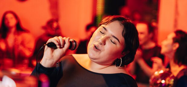 Carefree woman with eyes closed singing karaoke at bar
