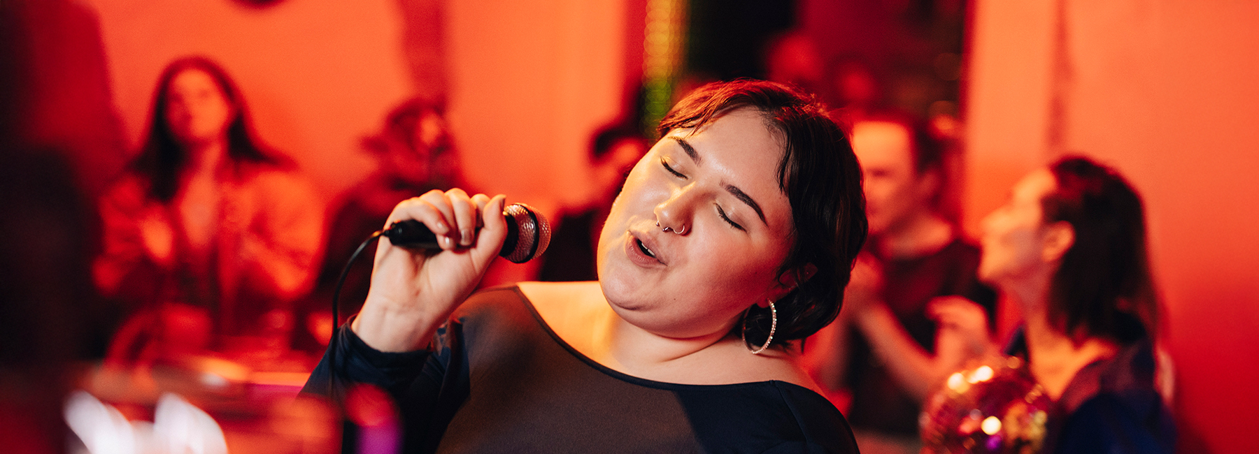 Carefree woman with eyes closed singing karaoke at bar