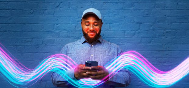 Man using smart phone in front of blue wall with converging light patterns