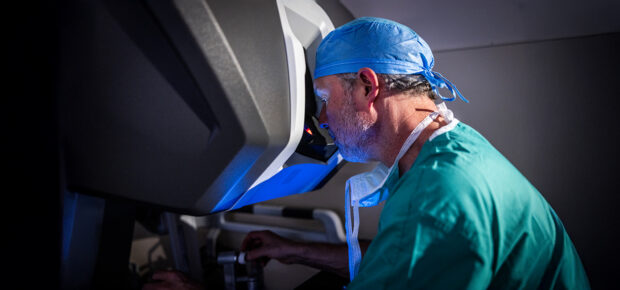 Male surgeon sitting at surgical robotic console