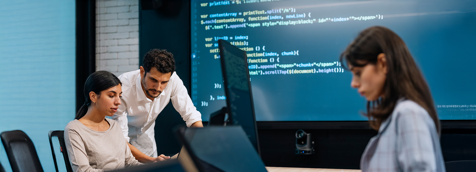 Software developer team working together, discussing on coding on multi computer screen. Software developers checking programming code on computer screen. working through a coding problem together.