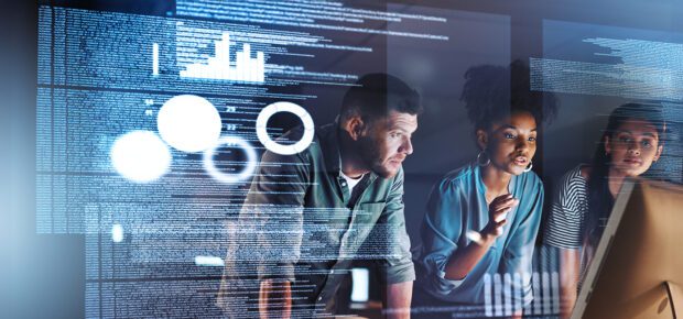 Technologists work together around a computer.