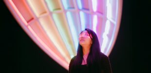 Confident Asian businesswoman wearing glowing glasses on a brightly lit street at night
